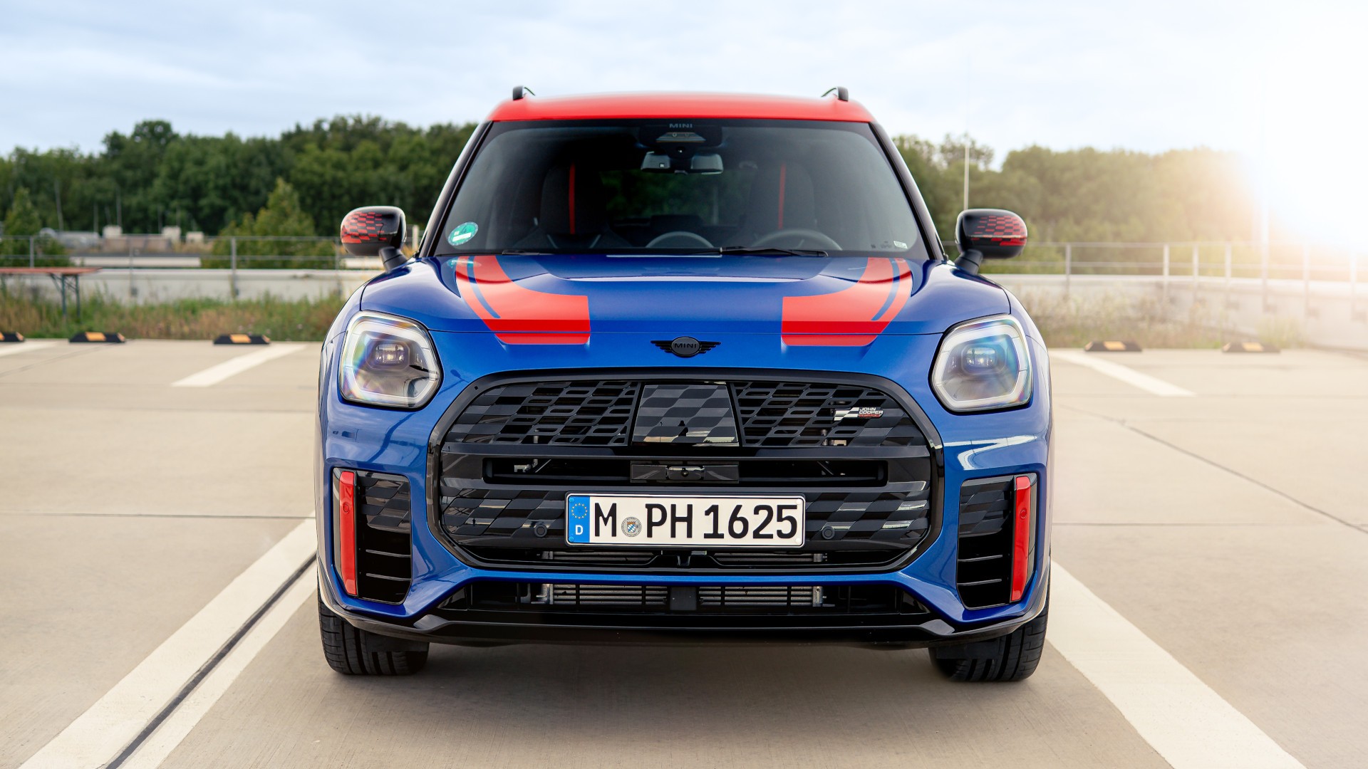 MINI Countryman in blazing blue mit JCW Folierung in chilli red, Frontalansicht.